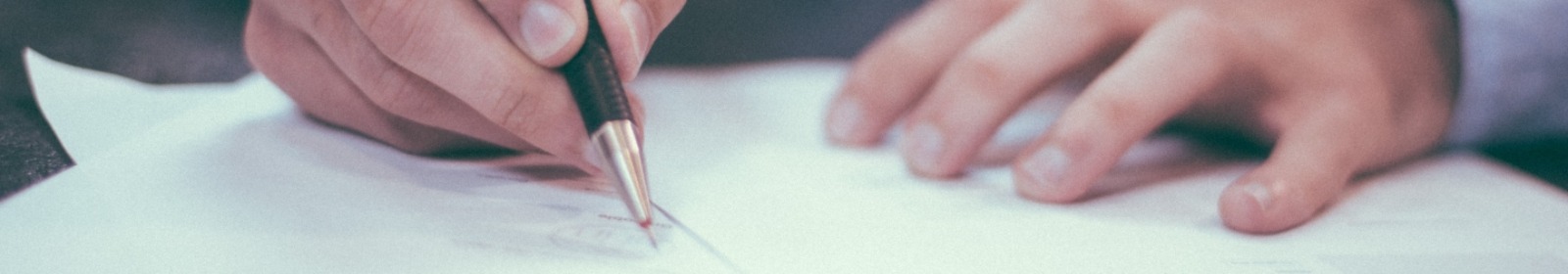 Person signing documents with a pen.