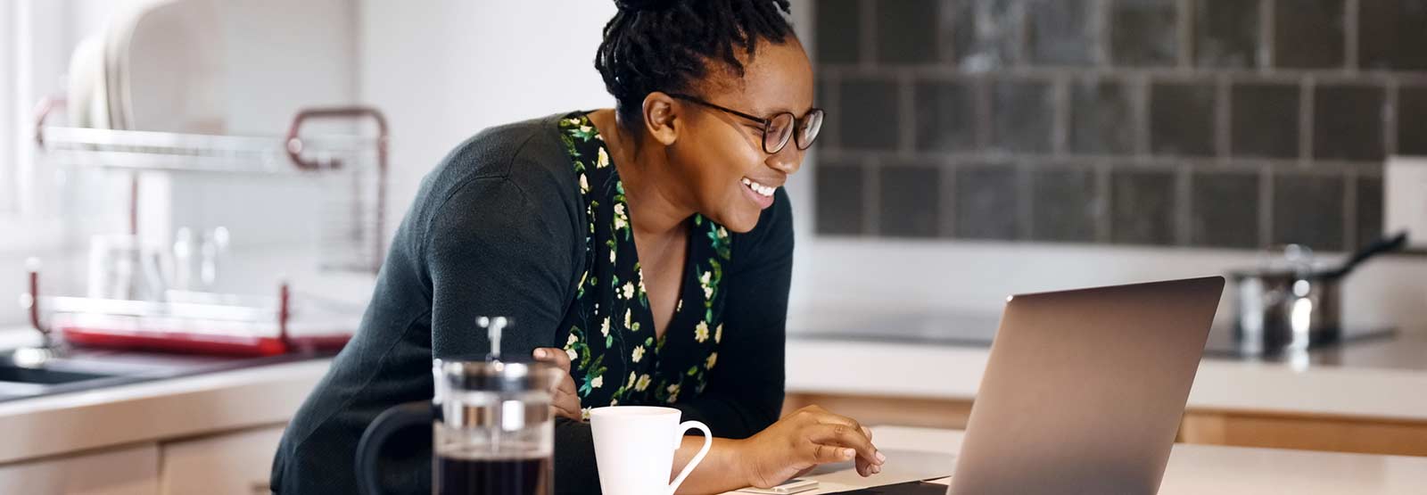 Woman using laptop in kitchen.