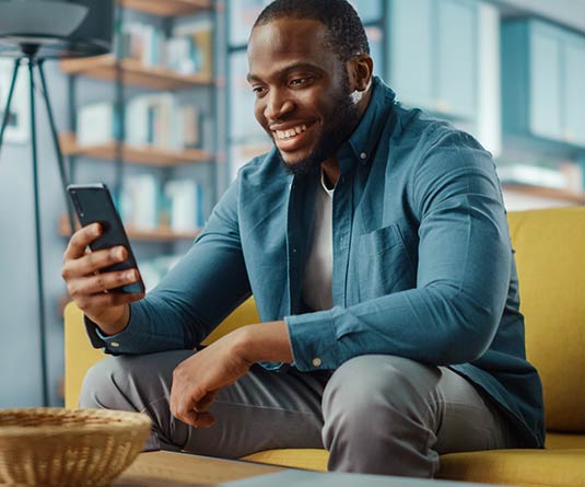 Man sitting on couch looking at mobile phone.