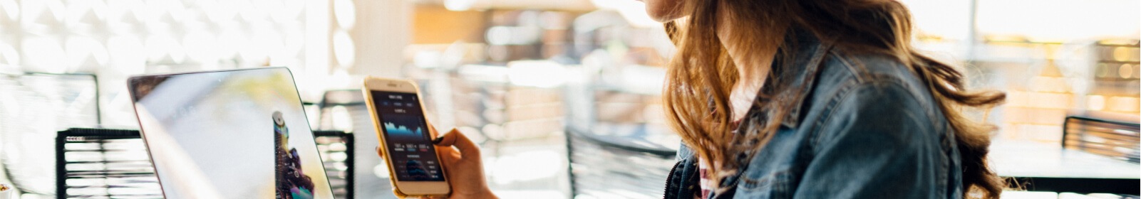 Woman sitting at computer using phone.