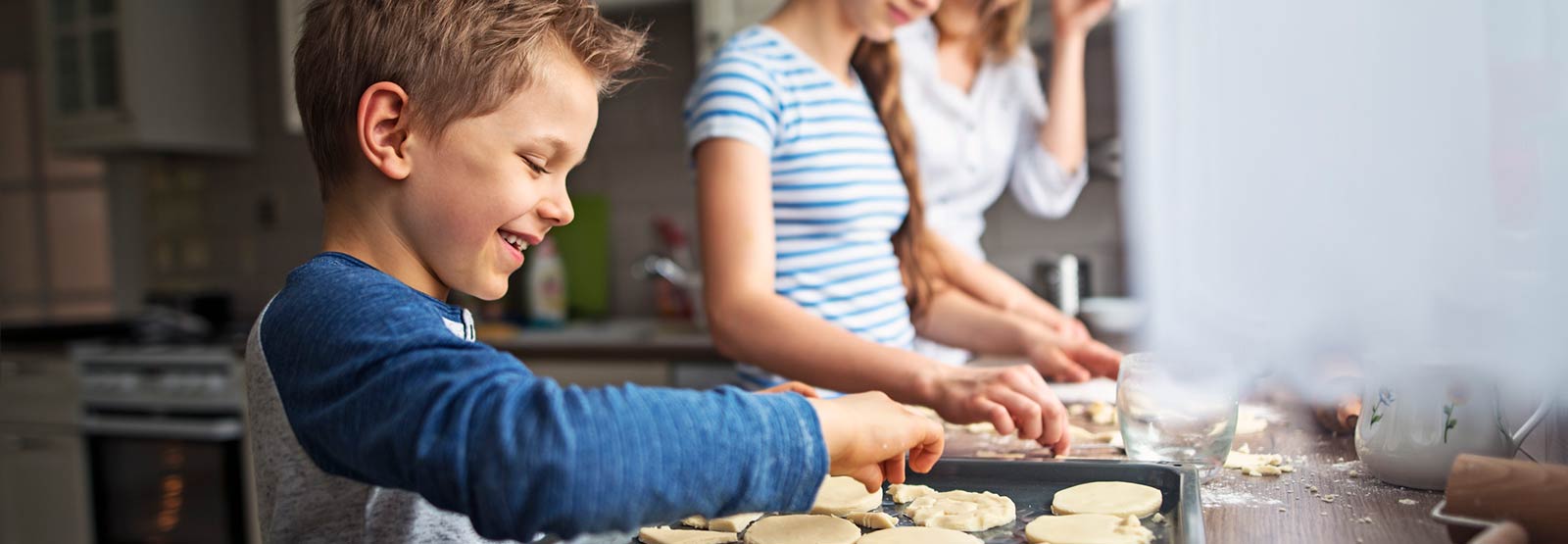 Boy making cookies with family at home.