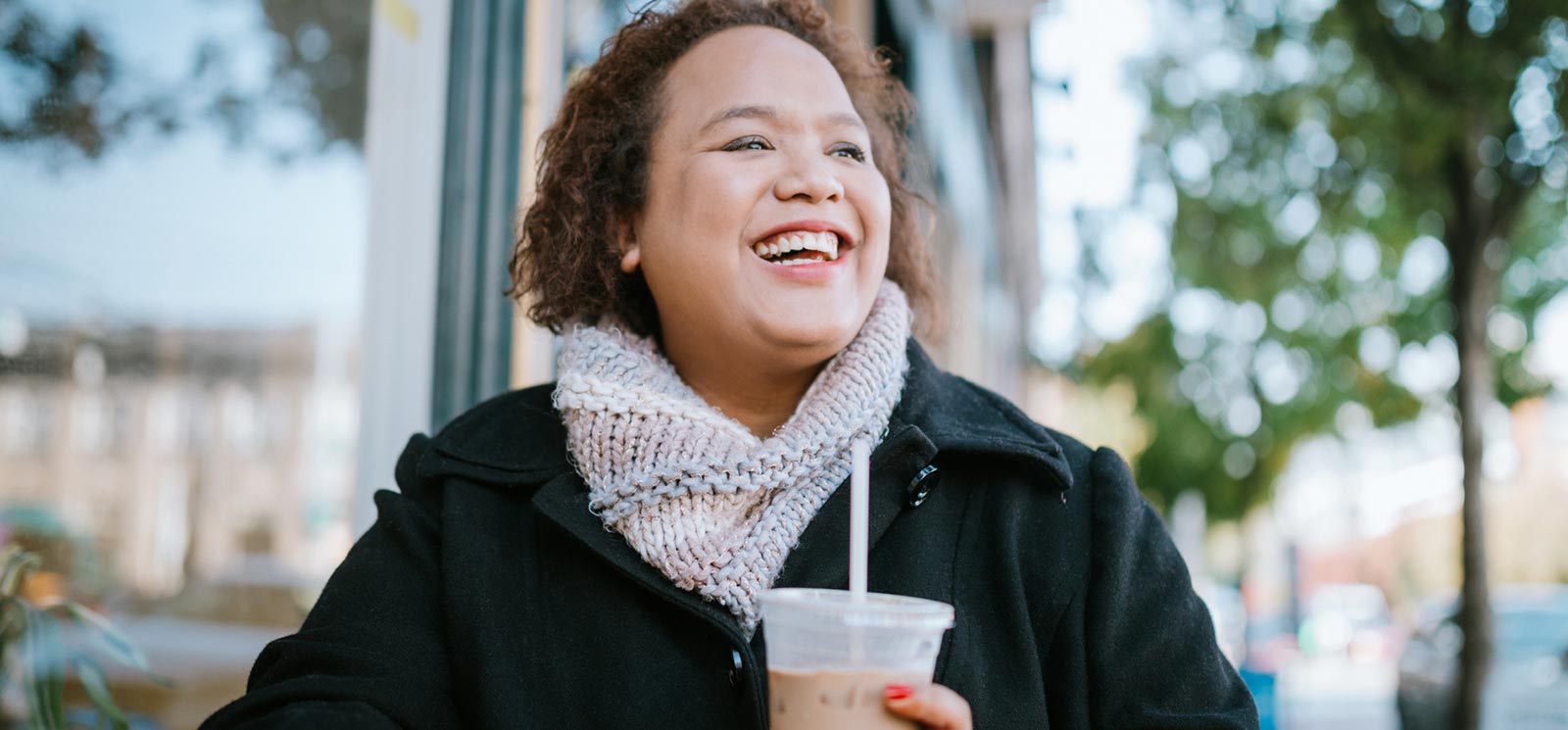 Woman smiling drinking iced coffee.