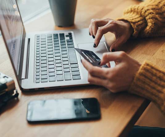 Woman holding card using laptop.